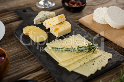 Variety of cheese and rosemary herbs on wooden table