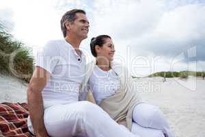 Happy couple sitting on sand at beach
