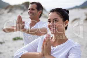 Couple performing yoga on beach