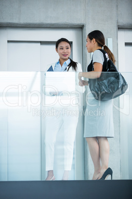 Businesswomen standing by elevator and having a conversation