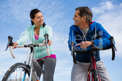 Couple leaning on bicycle while interacting with each other