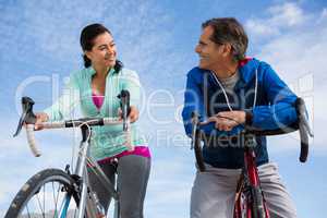 Couple leaning on bicycle while interacting with each other