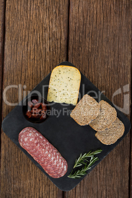 Salami, cheese, rosemary herbs and slices of brown bread on slate plate