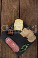 Salami, cheese, rosemary herbs and slices of brown bread on slate plate