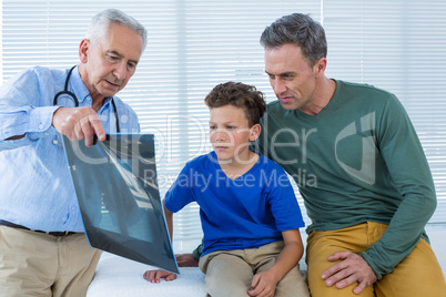 Doctor showing x-ray report to patient and his parent