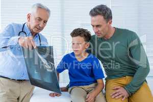 Doctor showing x-ray report to patient and his parent