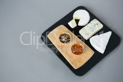 Variety of cheese with jam and fresh herbs on slate plate