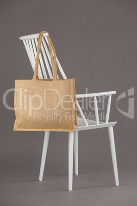 Beige fabric bag hanging on a white chair