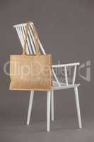 Beige fabric bag hanging on a white chair