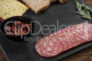 Salami, cheese and slices of brown bread on slate plate