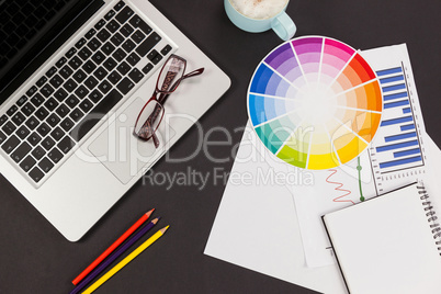 Laptop, spectacles, color pencils, color scheme chart, coffee cup, business graph and diary