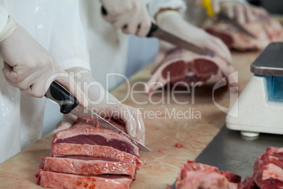 Butcher cutting meat at meat factory