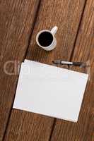 Cup of coffee with blank sheet of paper and pen