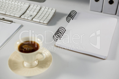 Cup of coffee with spiral notepad on table