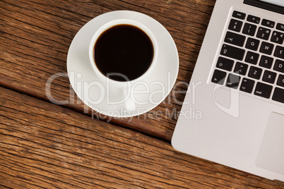 Laptop and cup of coffee on wooden table