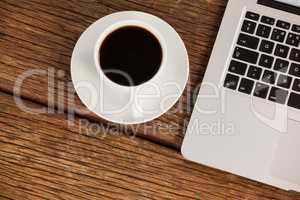 Laptop and cup of coffee on wooden table