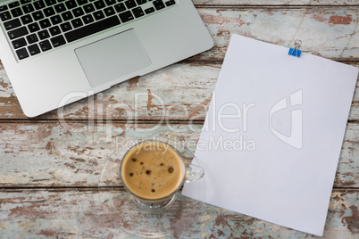 Laptop with blank paper and cup of coffee