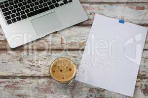 Laptop with blank paper and cup of coffee
