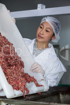 Butcher emptying tray with minced meat