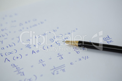 Pen over a sheet of paper with maths formulas