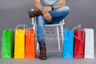 Man sitting on a chair with colorful shopping bags