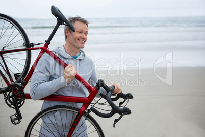 Man carrying bicycle on beach