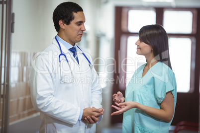 Doctor and surgeon interacting with each other in corridor