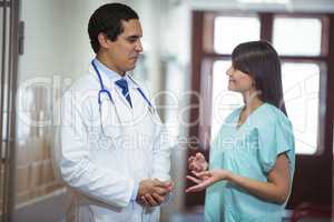 Doctor and surgeon interacting with each other in corridor
