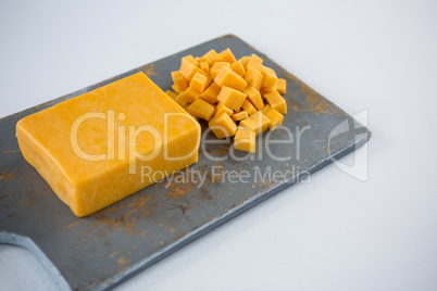 Block and cubes of cheese on chopping board
