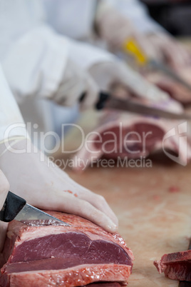 Butcher cutting meat at meat factory