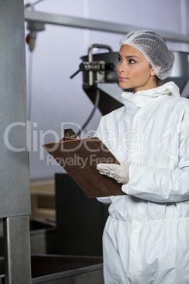 Female butcher maintaining records on clipboard