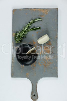 Sliced cheese and rosemary on chopping board