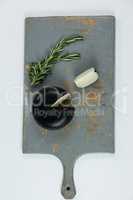 Sliced cheese and rosemary on chopping board