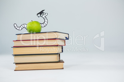 Conceptual image of books, apple and snake with graduate cap