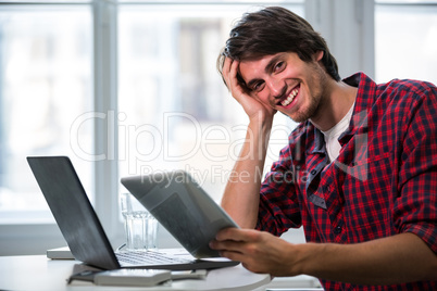 Graphic designer using laptop and digital tablet at his desk