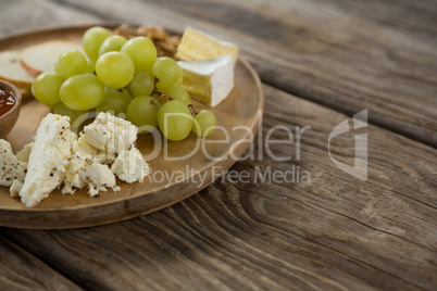 Cheese and grapes on wooden plate