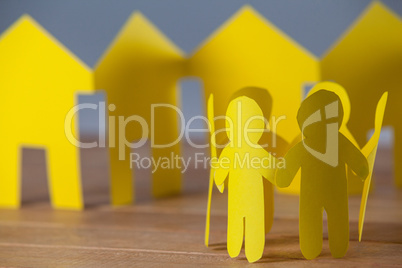 Paper cutout people standing in a circle against paper houses