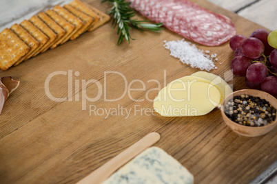 Roquefort cheese, biscuits and ham with various ingredients on chopping board