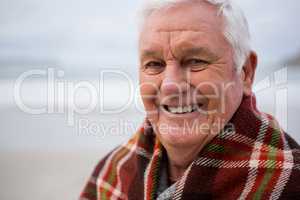 Portrait of senior man wrapped in shawl on beach