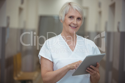 Female nurse using digital tablet in corridor