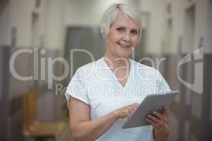 Female nurse using digital tablet in corridor