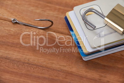 Bunch of credit cards, fishing hook and lock on wooden background