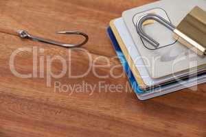 Bunch of credit cards, fishing hook and lock on wooden background