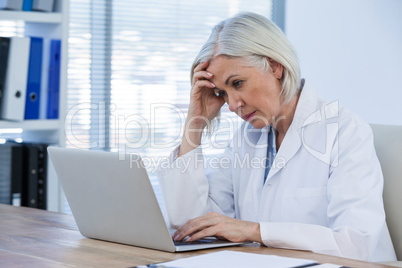 Tense female doctor working on her laptop