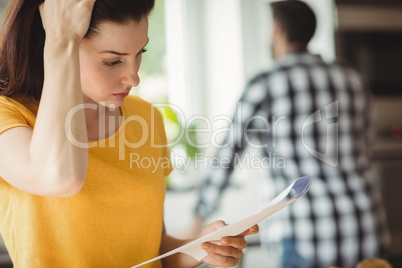 Tensed woman checking bill in kitchen