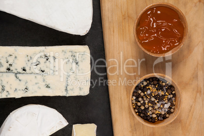 Sliced cheese, bowls of jam and spices on chopping board