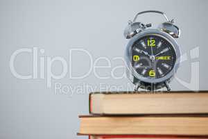 Alarm clock placed on stack of books