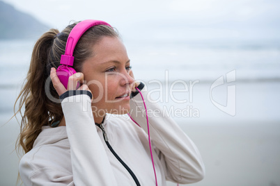 Beautiful woman listening music on headphones at beach