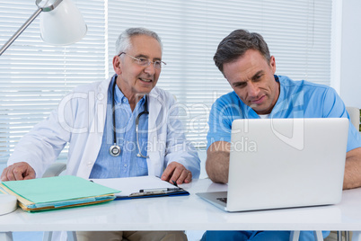 Surgeon and doctor discussing over laptop