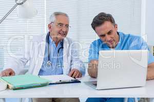 Surgeon and doctor discussing over laptop